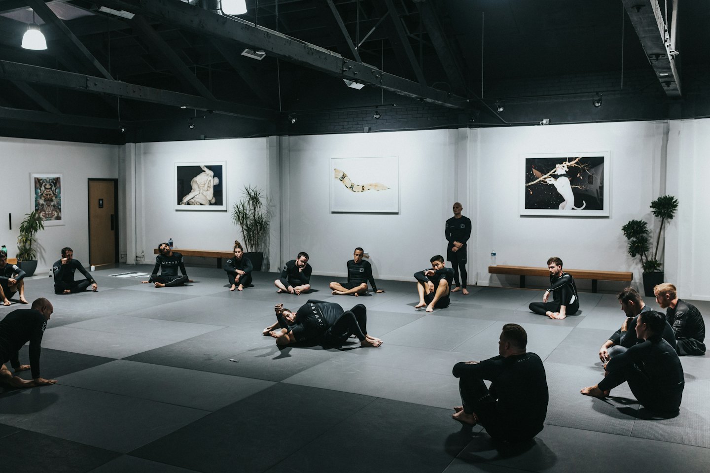 Adults in athletic wear resting on mats in a modern studio.